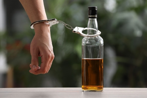 person handcuffed to a bottle of alcohol